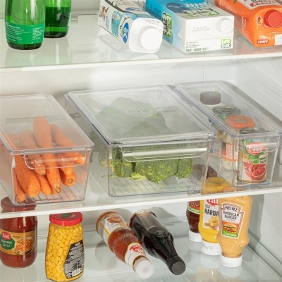 Caixas transparentes com legumes e conservas dentro de frigorífico organizado