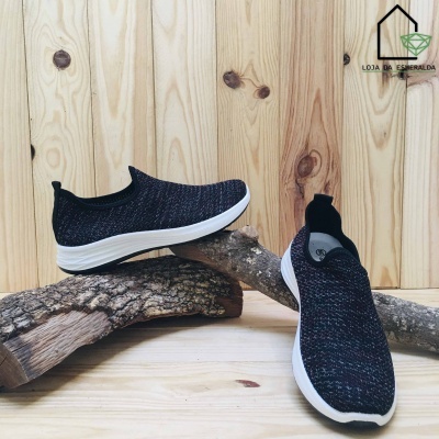 Sapatos desportivos slip-on tricotados em cores escuras com sola branca sobre troncos de madeira