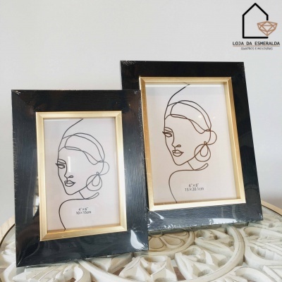 Dois porta-retratos pretos com borda dourada e desenhos de rostos femininos em linhas simples