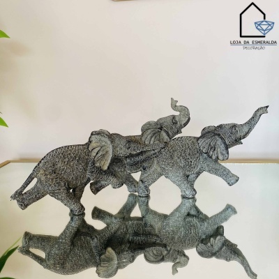 Esculturas texturizadas de elefantes cinzentos sobre superfície espelhada com logotipo de loja no fundo