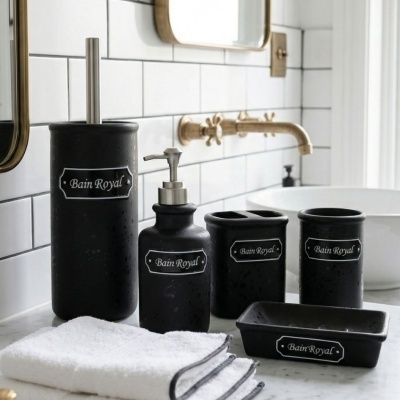 Acessórios de casa de banho em cerâmica preta com etiqueta Bain Royal num ambiente com bancada de mármore e azulejos brancos.