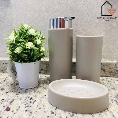 Conjunto de acessórios de casa de banho bege com planta artificial em vaso branco em bancada de mármore cinza
