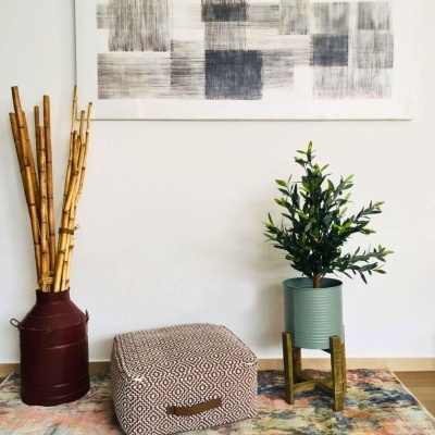 Vaso metálico com bambu, pufe geométrico, planta em vaso azul com suporte, quadro abstrato preto e branco