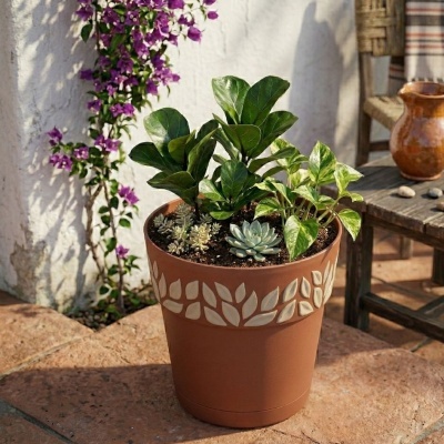 Vaso cerâmica castanha com plantas verdes e suculentas, padrão folhas branco, em superfície de pedra
