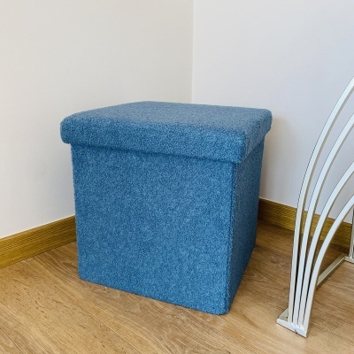 Pufe quadrado azul em canto de divisão com chão de madeira