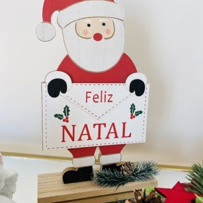 Peça decorativa de Natal em madeira com figura de Pai Natal e cartaz 'Feliz NATAL'.