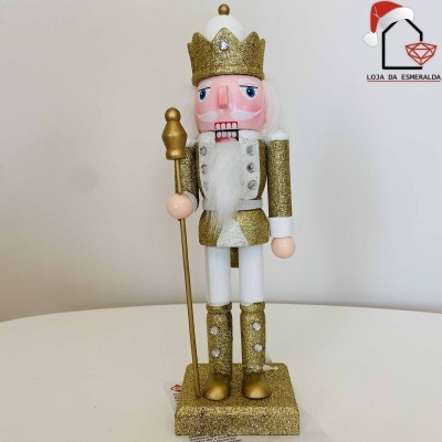 Quebra-Nozes dourado decorativo com coroa e cetro, sobre base branca e fundo bege.