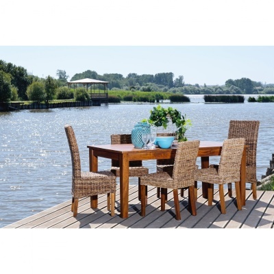 Conjunto de mesa e cadeiras de madeira e rattan natural numa plataforma de madeira perto da água