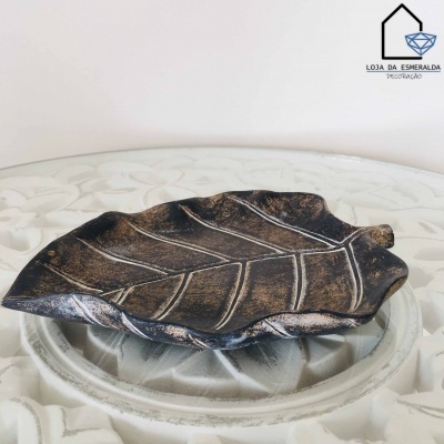 Prato decorativo em forma de folha castanho escuro com detalhes em bronze sobre mesa branca decorada