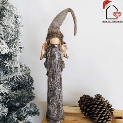 Anjo decorativo rústico com vestido cinzento e chapéu castanho junto a pinhas e árvore de Natal