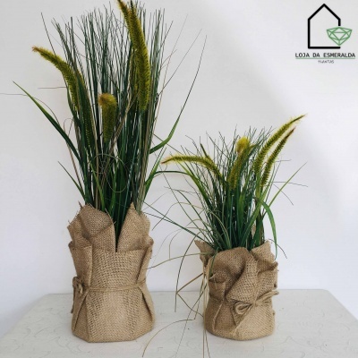 Duas plantas decorativas em vasos com tecido rústico castanho em fundo branco com logótipo da loja