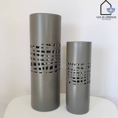 Dois vasos cilíndricos cinzentos com padrão geométrico vazado, colocados numa superfície branca.