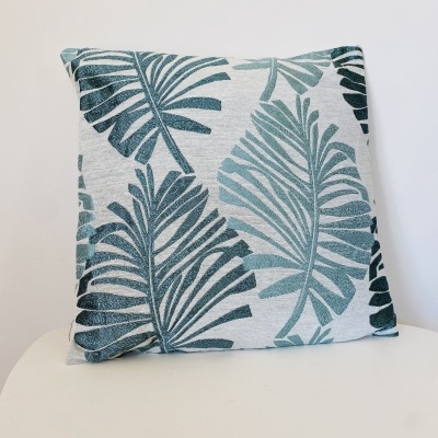 Almofada decorativa com padrão de folhas verdes em fundo cinza claro
