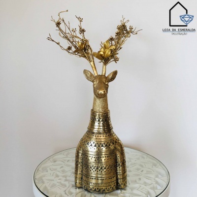 Escultura decorativa de veado dourado com galhos secos dourados sobre mesa de vidro