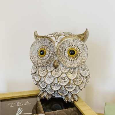 Figura decorativa de coruja em cerâmica ou resina com textura detalhada e olhos amarelos