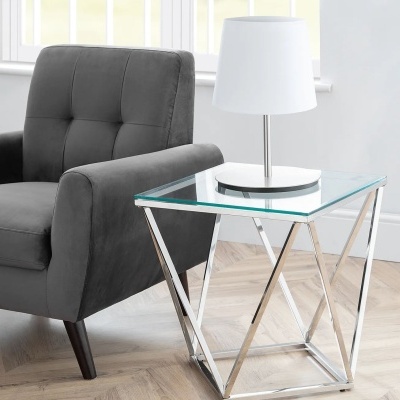 Cadeira cinzenta ao lado de mesa de apoio de vidro com lâmpada branca