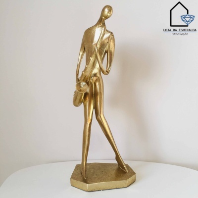 Figura decorativa dourada estilizada a tocar saxofone com base hexagonal