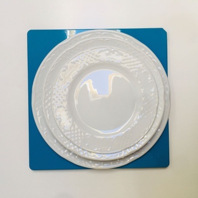 Três pratos brancos em cerâmica com padrão em relevo sobre base azul.