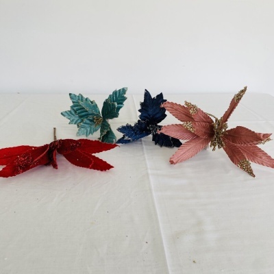 Três raminhos decorativos com folhas coloridas e brilhantes sobre toalha branca.