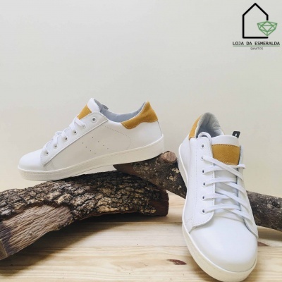 Par de sapatilhas brancas com detalhes castanhos sobre madeira