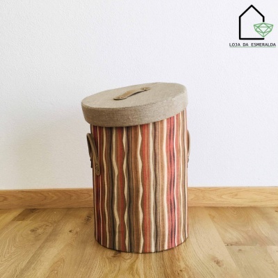 Cesto de tecido com tampo texturado e padrões verticais em tons terra sobre chão de madeira