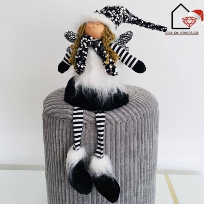 Boneca decorativa natalícia com roupas pretas e brancas sentada em puff cinzento
