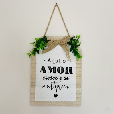 Placa decorativa com texto e folhas verdes pendurada na parede