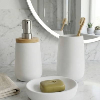 Conjunto de acessórios brancos de casa de banho em cerâmica com escovas de dentes de madeira e sabonete verde.