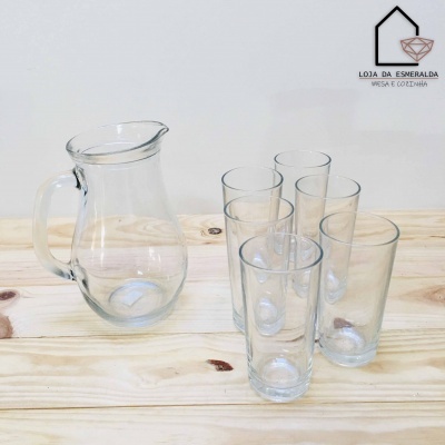 Jarro de vidro com pega e cinco copos altos em vidro sobre mesa de madeira clara
