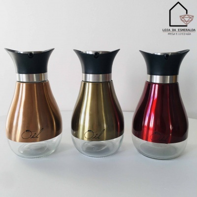 Três dispensadores de óleo metálicos bronze, dourado e vermelho com base de vidro