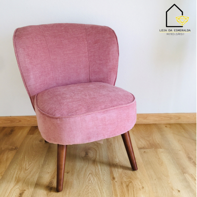 Cadeira estofada cor de rosa com pernas de madeira num chão de madeira
