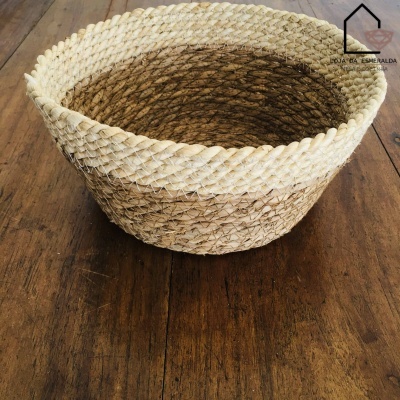 Cesto redondo em fibras naturais sobre mesa de madeira