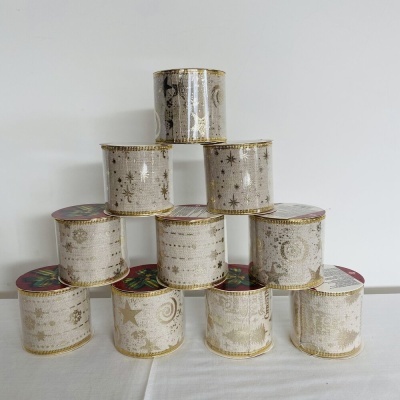 Rolos de fita decorativa branca com padrões dourados empilhados em pirâmide