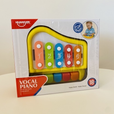 Brinquedo piano vocal colorido infantil em caixa branca com detalhes vermelhos e imagem de criança