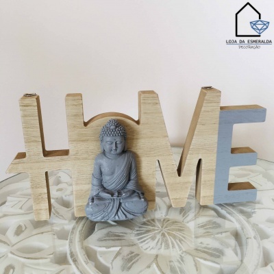 Decoração de madeira formando a palavra LOVE com estátua de Buda cinza no centro.