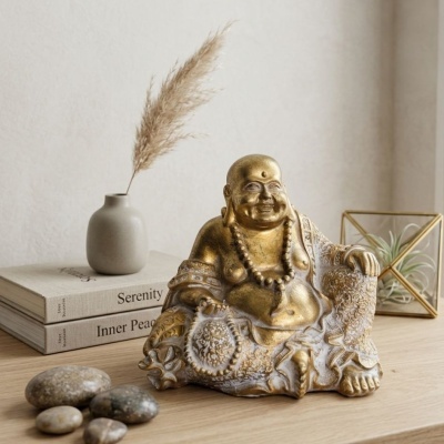 Estátua de Buda dourada e branca sobre superfície de madeira com livros, pedras e vasos