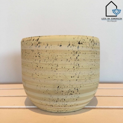 Vaso de cerâmica bege com salpicos pretos em suporte de madeira clara