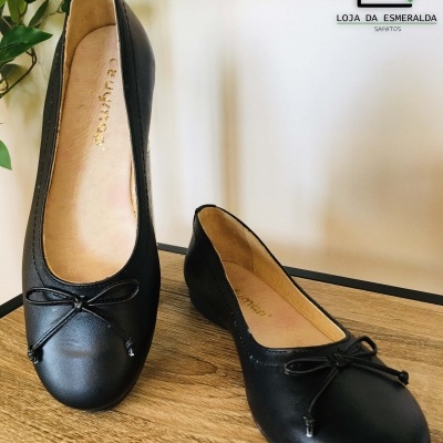 Sapatilhas pretas com laço numa superfície de madeira