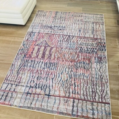 Tapete colorido abstrato sobre chão de madeira ao lado de sofá creme