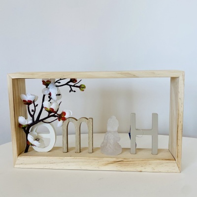 Expositor de madeira com flores artificiais e letras decorativas 'HOME' com figura de Buda.