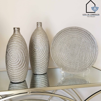 Dois jarros e um prato redondo prateados com textura espiral em superfície espelhada