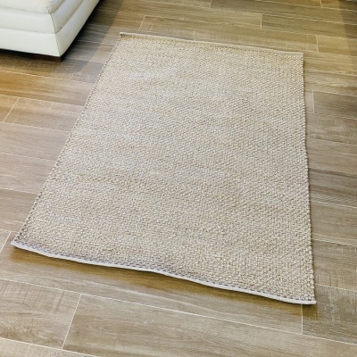 Tapete bege trançado sobre chão de madeira clara ao lado de sofá branco