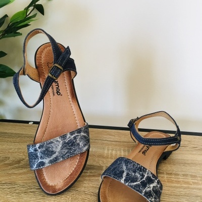 Par de sandálias femininas com padrão marmorizado e tiras pretas sobre superfície de madeira.