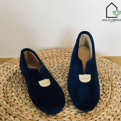 Chinelos azul escuro com etiqueta bege sobre tapete redondo de fibras naturais