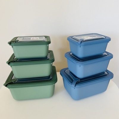 Caixas plásticas empilhadas verdes e azuis com tampas e fechos herméticos
