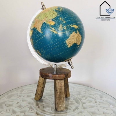 Globo terrestre azul sobre base de madeira rústica em mesa de vidro
