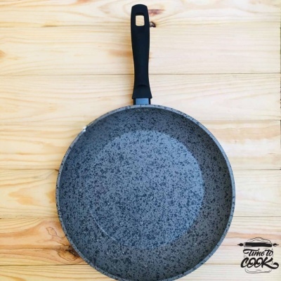 Frigideira antiaderente cinza com cabo preto sobre madeira