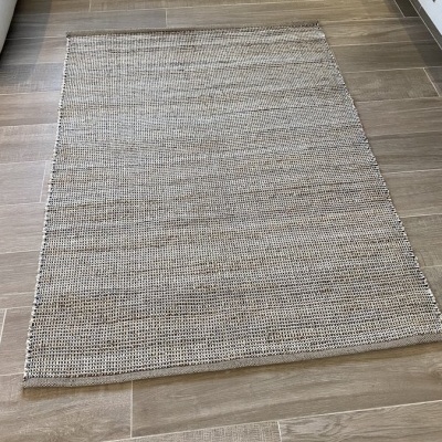 Tapete retangular bege e cinza sobre pavimento de madeira clara