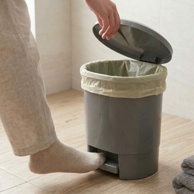 Contentor de lixo cinzento com tampa aberta e saco bege acionado por pedal.
