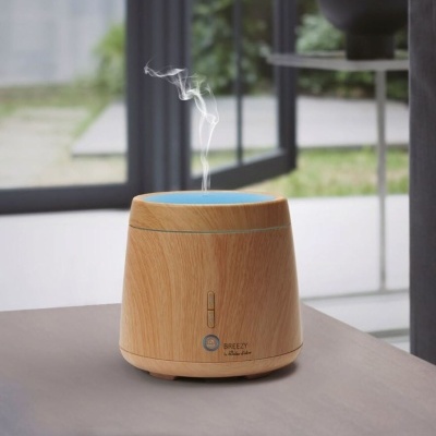 Difusor de madeira clara com vapor visível sobre mesa